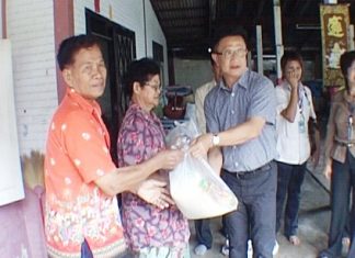 Deputy Mayor Wutisak Rermkitkarn, centre right, hands over relief supplies to Naklua resident Viang Saengthong, left, after the latter’s house was badly damaged during a Feb. 15 rainstorm.